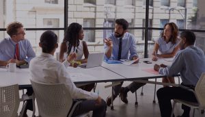 several business men and women seated around a conference table having a discussion