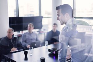 businessman standing and looking at a screen while training three other men