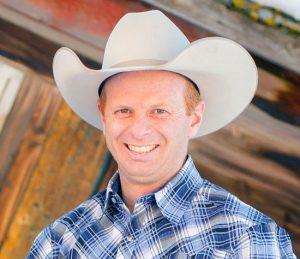 owner of High West Project Management Zac Davis is a button up shirt and cowboy hat smiling